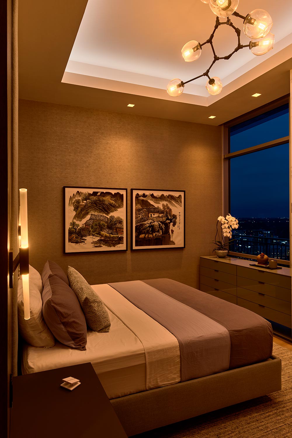 Modern bedroom with warm ambient lighting and framed landscape art