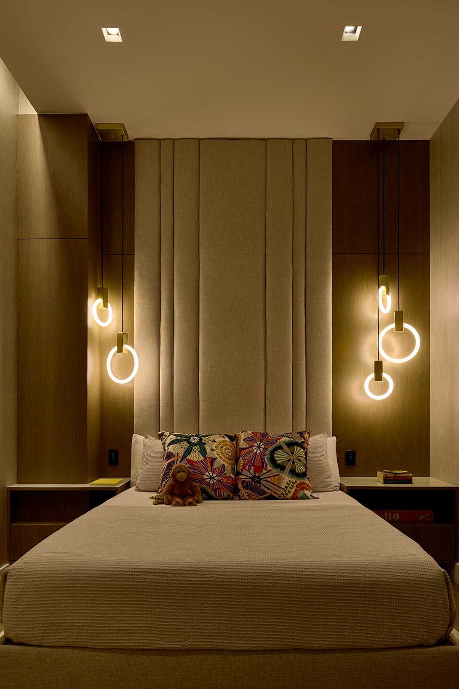 Bedroom with a tall channeled headboard and glowing circular pendant lights