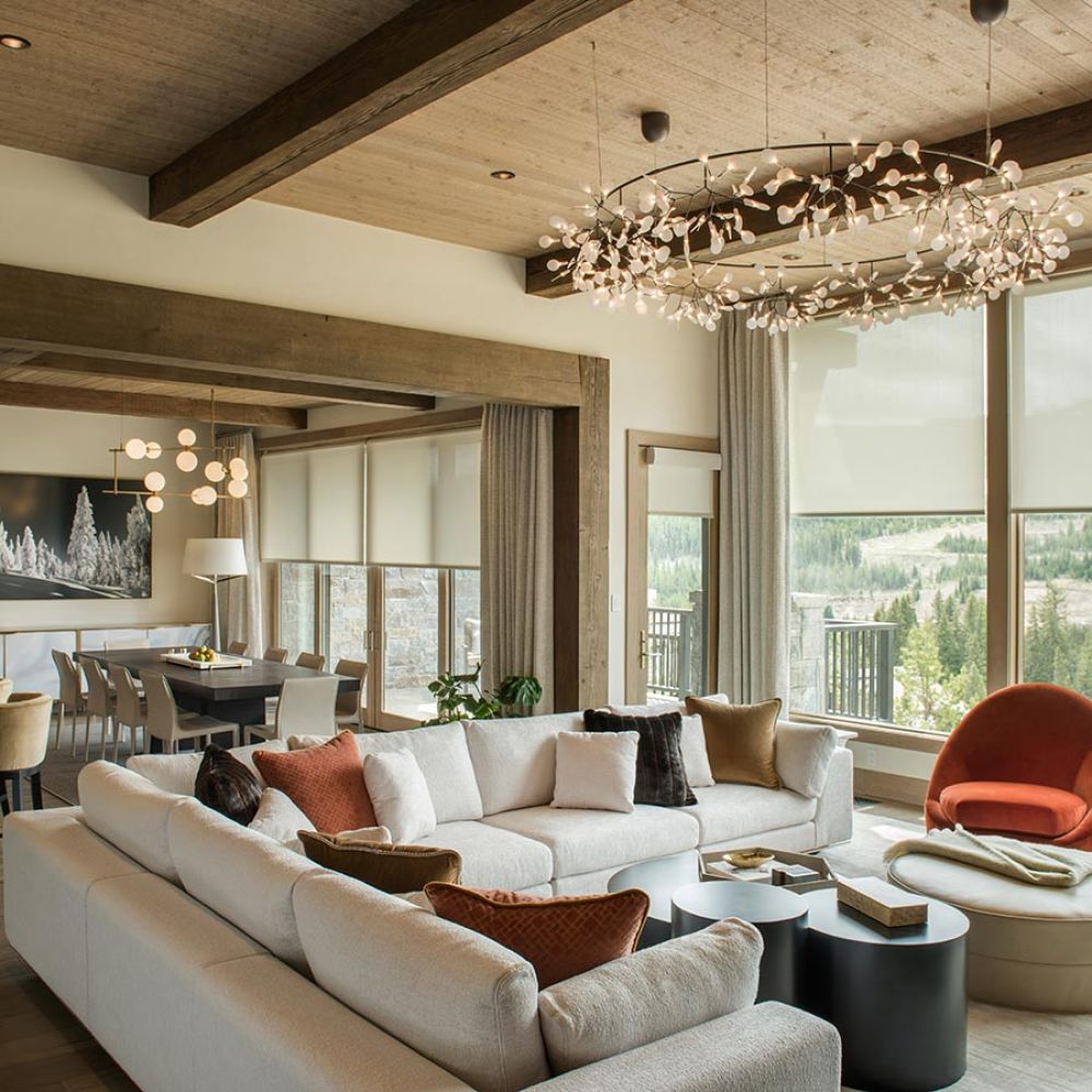 Large open living area with a floral chandelier, sectional sofa, and mountain views